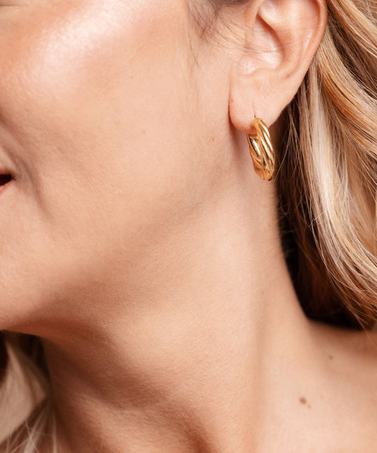 Dettaglio profilo donna che indossa orecchini a cerchio torchon Waves in oro, look elegante - Suntime Moda