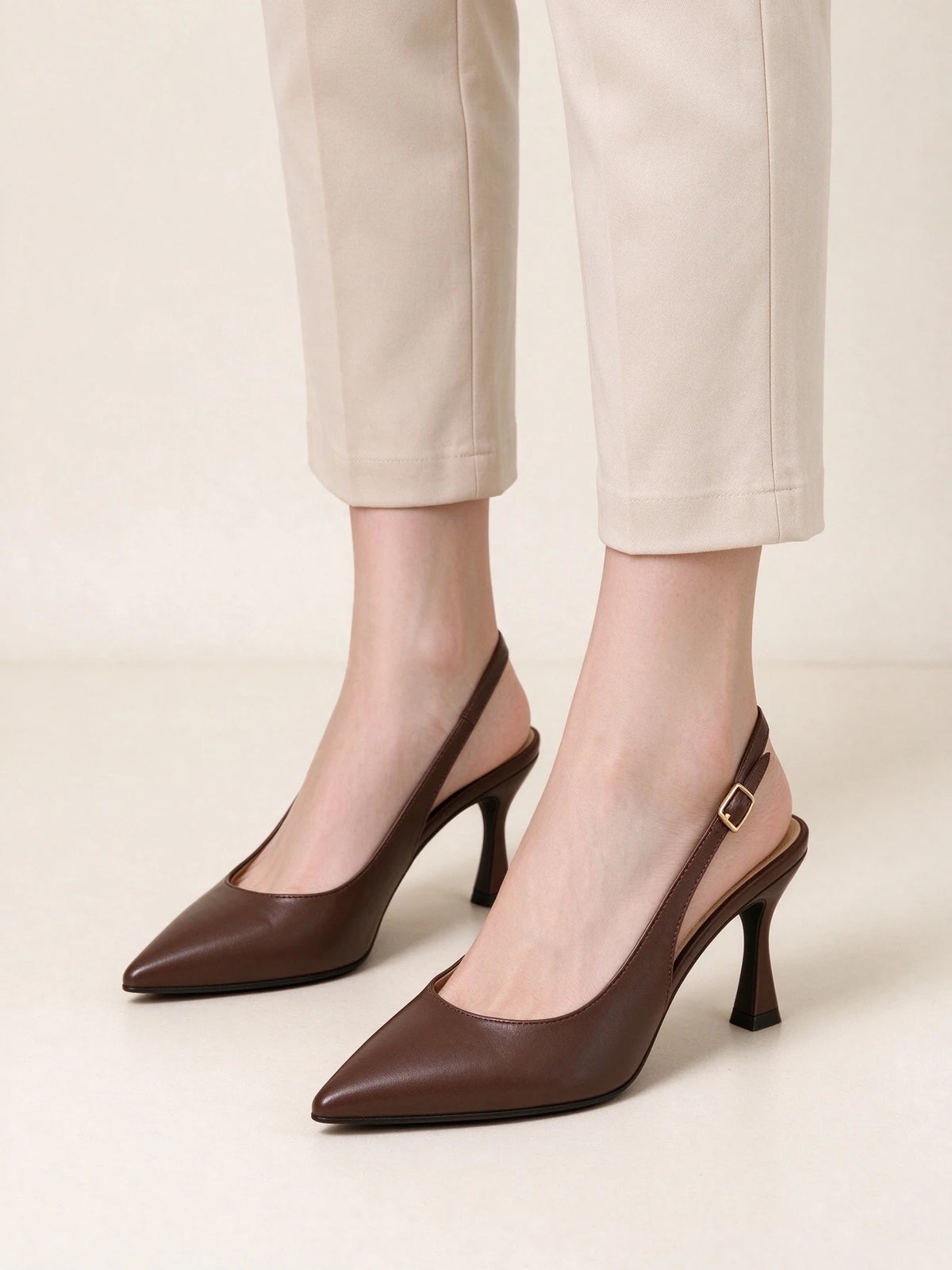 Modella che indossa scarpe slingback marroni a punta con cinturino posteriore, abbinate a pantaloni classici beige - SUNTIMEMODA