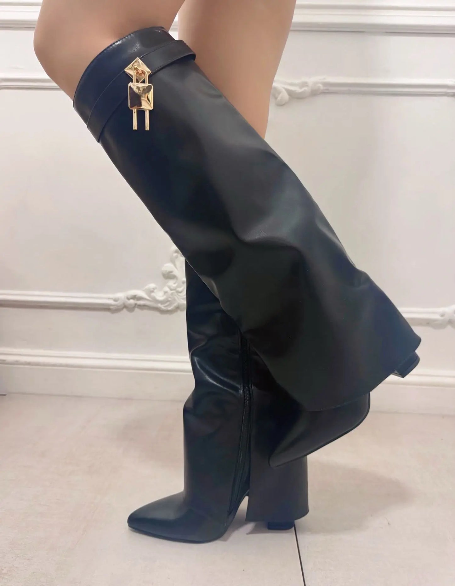 Donna che indossa stivali alti neri in ecopelle con design a tubo, punta sfilata, dettaglio lucchetto dorato e tacco largo da 10,5 cm - SUNTIMEMODA