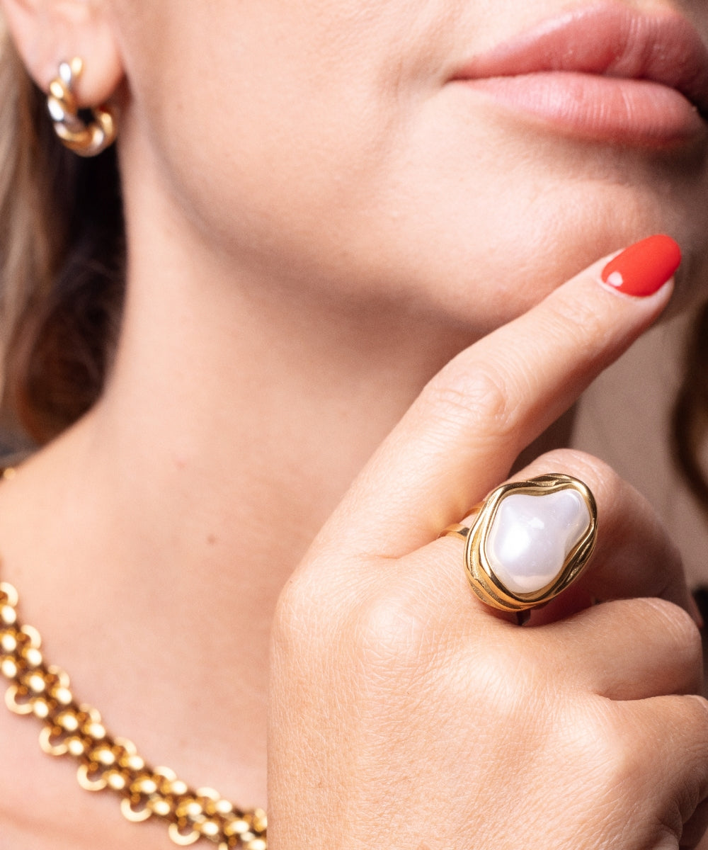 Dettaglio anello madreperla irregolare indossato su mano con smalto rosso, look elegante e naturale - Suntime Moda