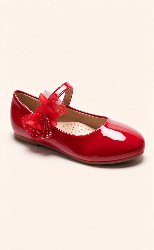 Scarpetta ballerina per bambina in vernice rosso fuoco brillante, decorata con fiore in tulle e perline pendenti sul cinturino, isolata su sfondo chiaro - SUNTIMEMODA