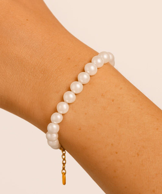 Donna che indossa un bracciale di perle bianche classiche sul polso, look elegante e raffinato - Suntime Moda