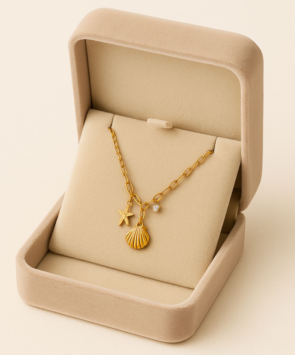 Collana Ibiza con ciondoli marini adagiata nella confezione regalo beige, dettaglio stella e conchiglia dorata - Suntime Moda