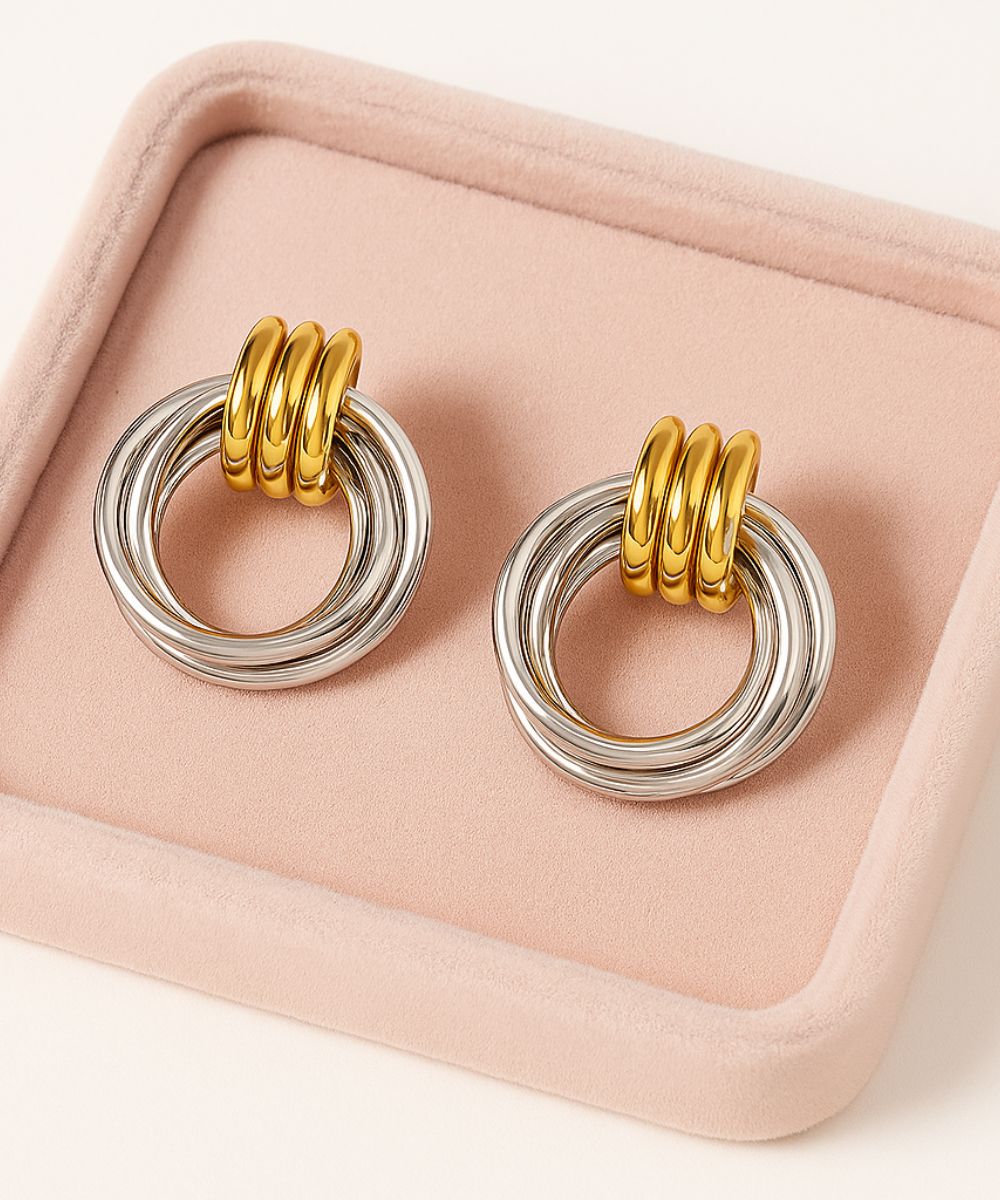 Close-up degli orecchini Sammy su espositore in velluto rosa, dettaglio della finitura lucida dei cerchi in oro e argento - Suntime Moda