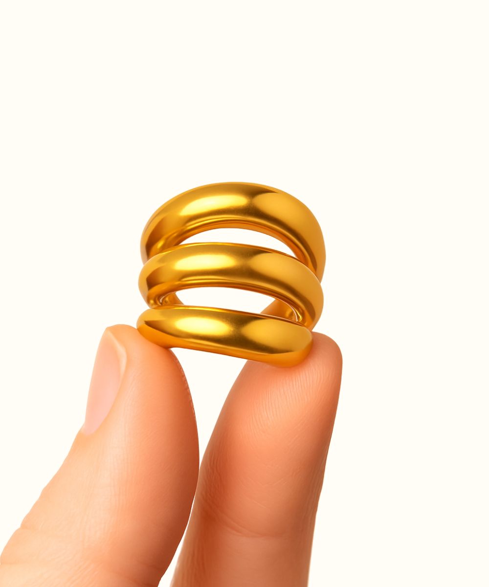 Dettaglio ear cuff Tris color oro tenuto tra le dita per mostrare il design a tripla fascia e lo spessore - Suntime Moda