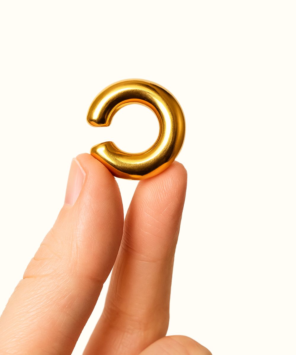 Dettaglio ear cuff basic oro tenuto tra le dita per mostrare lo spessore e la forma a C - Suntime Moda