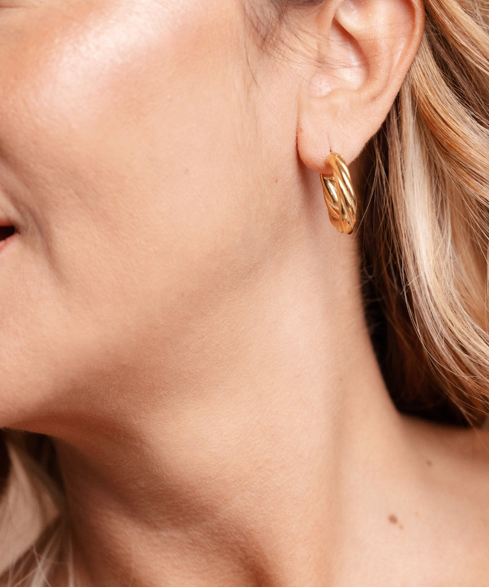 Dettaglio profilo donna che indossa orecchini a cerchio torchon Waves in oro, look elegante - Suntime Moda