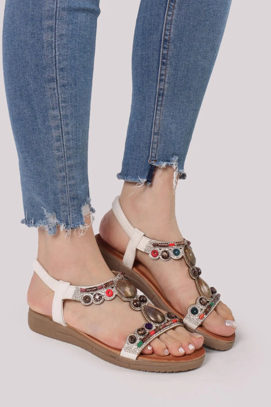 Donna che indossa sandali bianchi stile etnico decorati con pietre colorate e strass, abbinati a jeans - SUNTIMEMODA