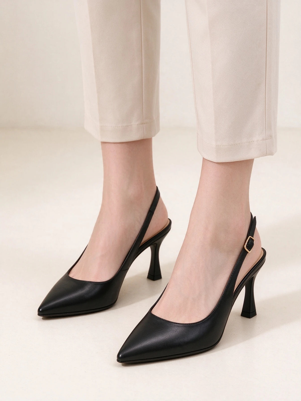 Modella che indossa slingback nere a punta con tacco, abbinate a pantaloni sartoriali chiari alla caviglia - SUNTIMEMODA