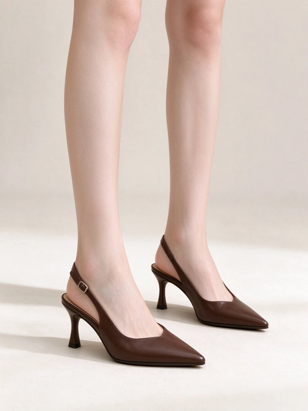 Modella che indossa eleganti décolleté slingback marrone scuro a punta con tacco alto e cinturino posteriore, vista laterale - SUNTIMEMODA